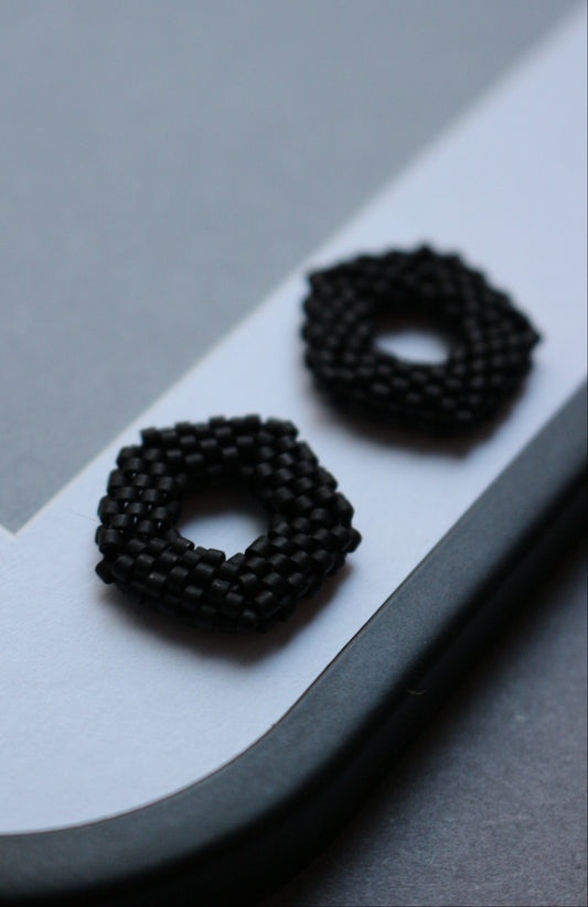 Black textured elements for earrings on a light gray background