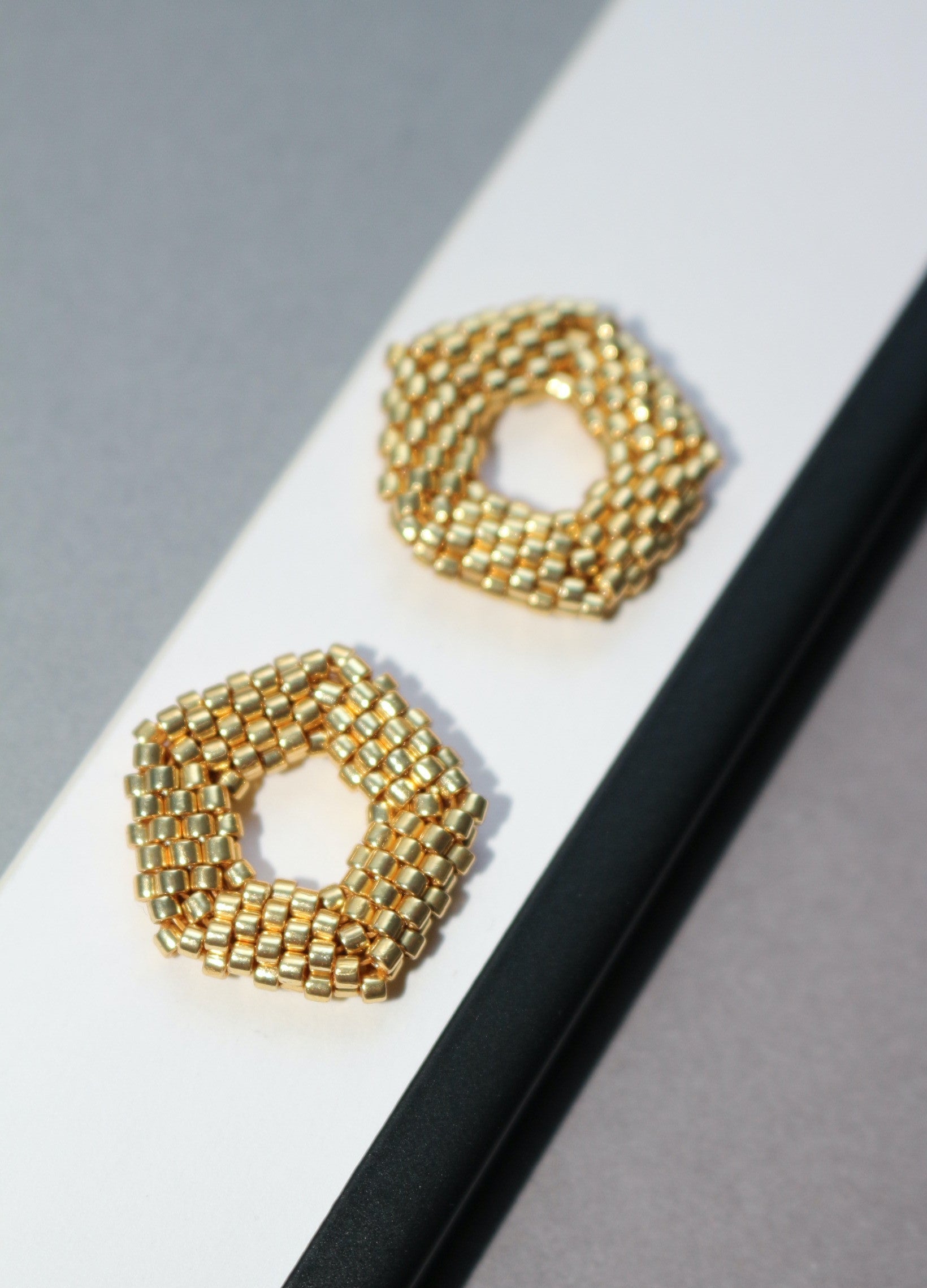 Gold tone pentagon element on a white and white background