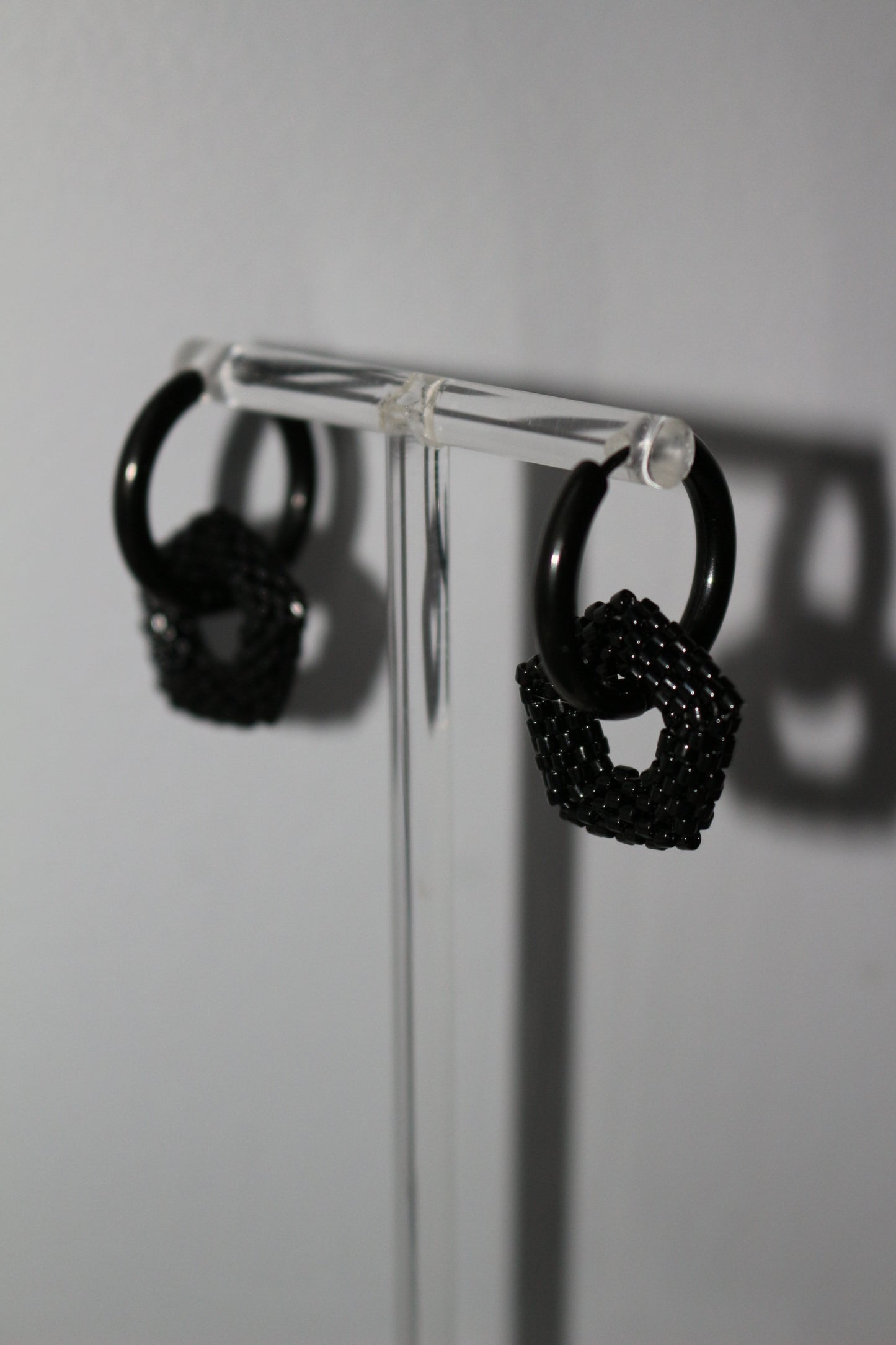 Black hoop with pentagon element on  a clear stand on a white background