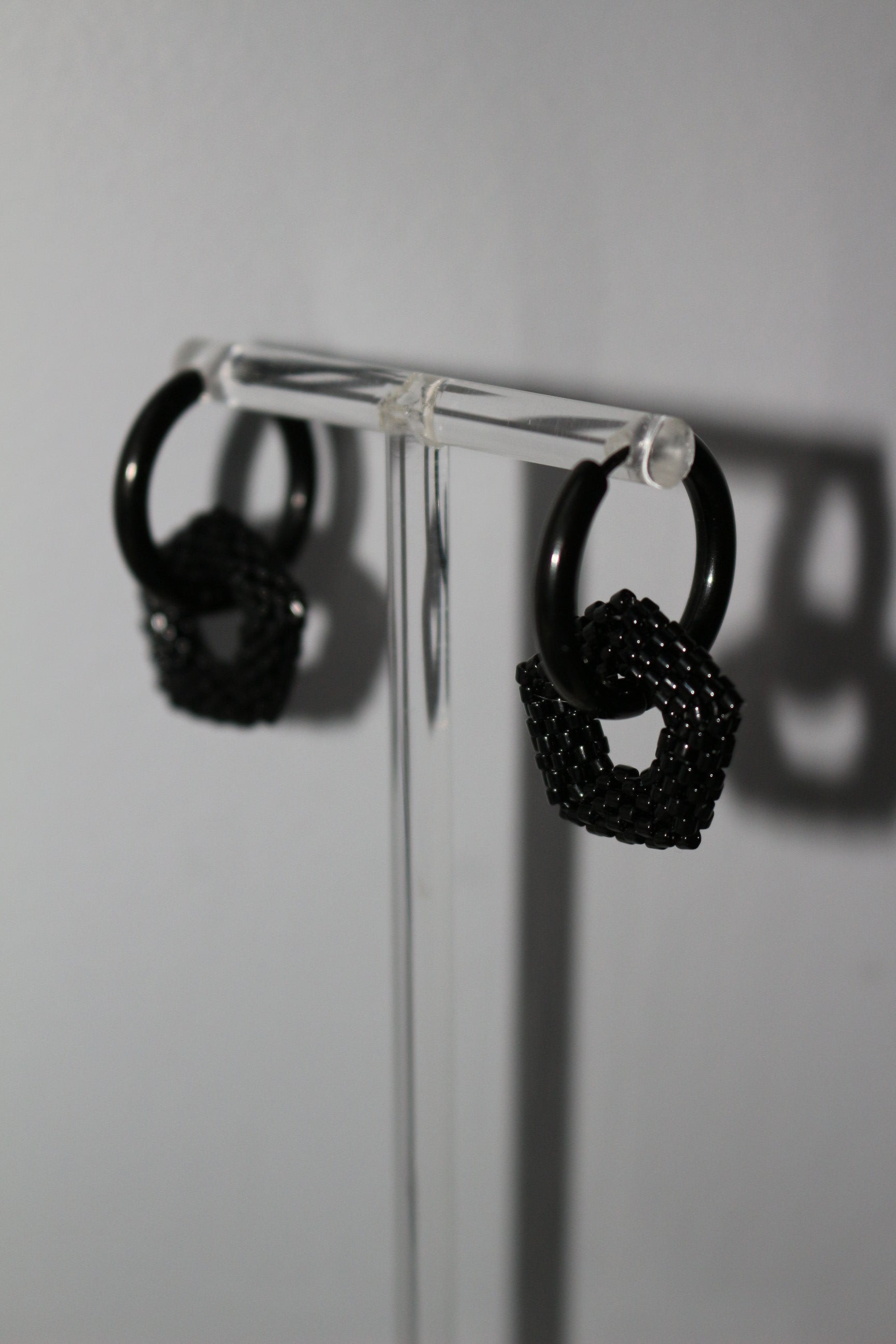 Black hoop with pentagon element on  a clear stand on a white background