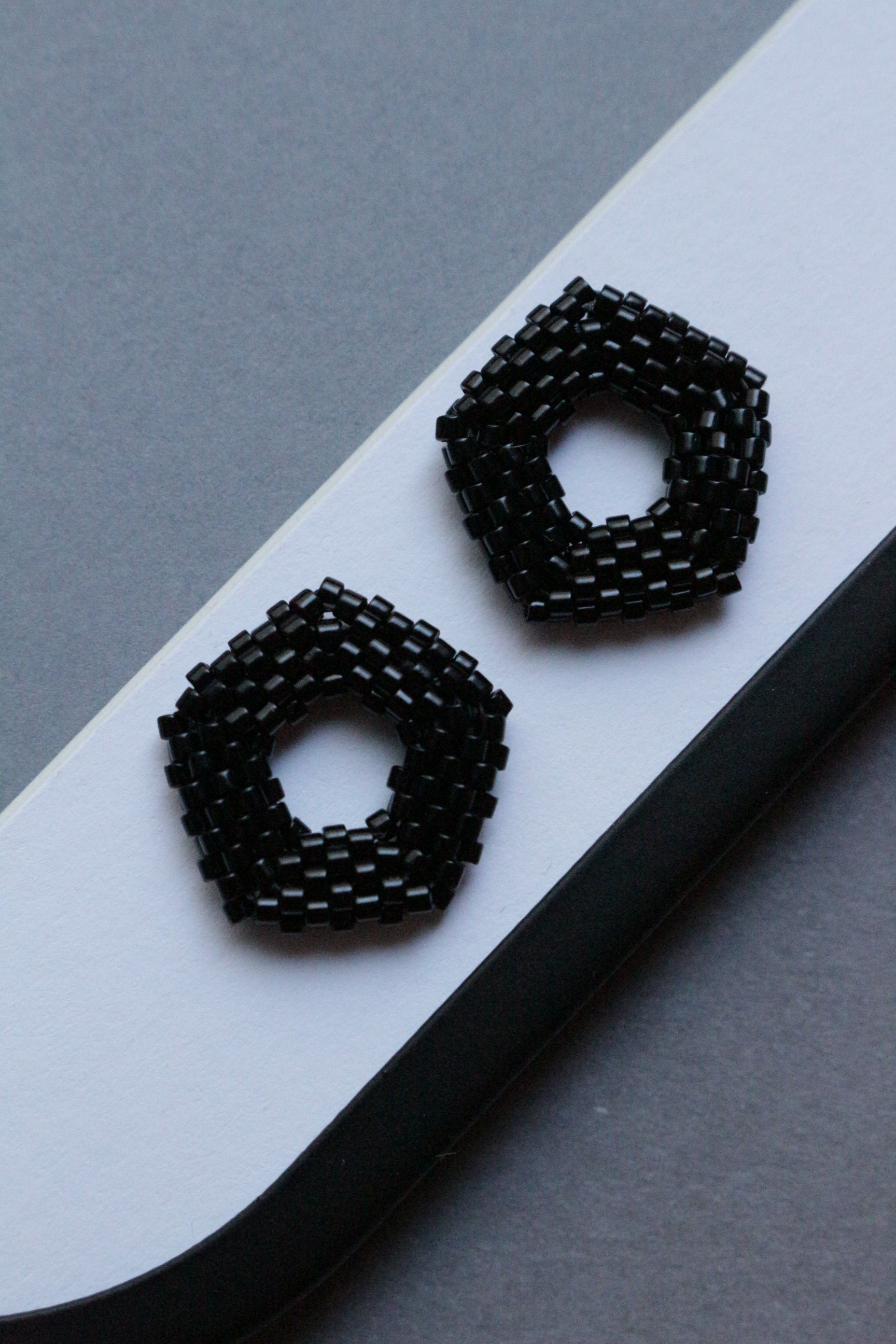 Black beaded earrings on a white and gray background