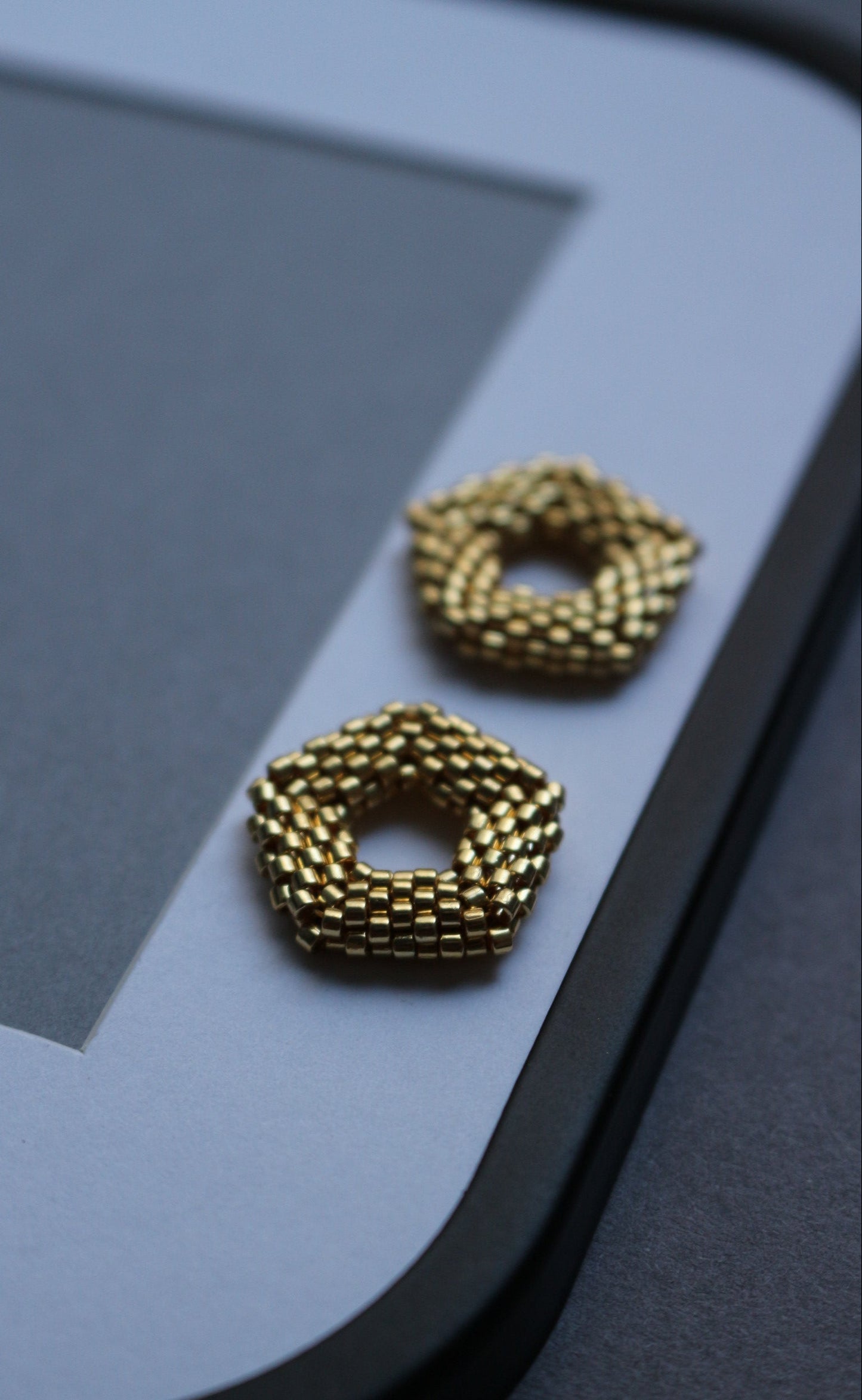 Gold earrings on a light gray surface with a blurred background