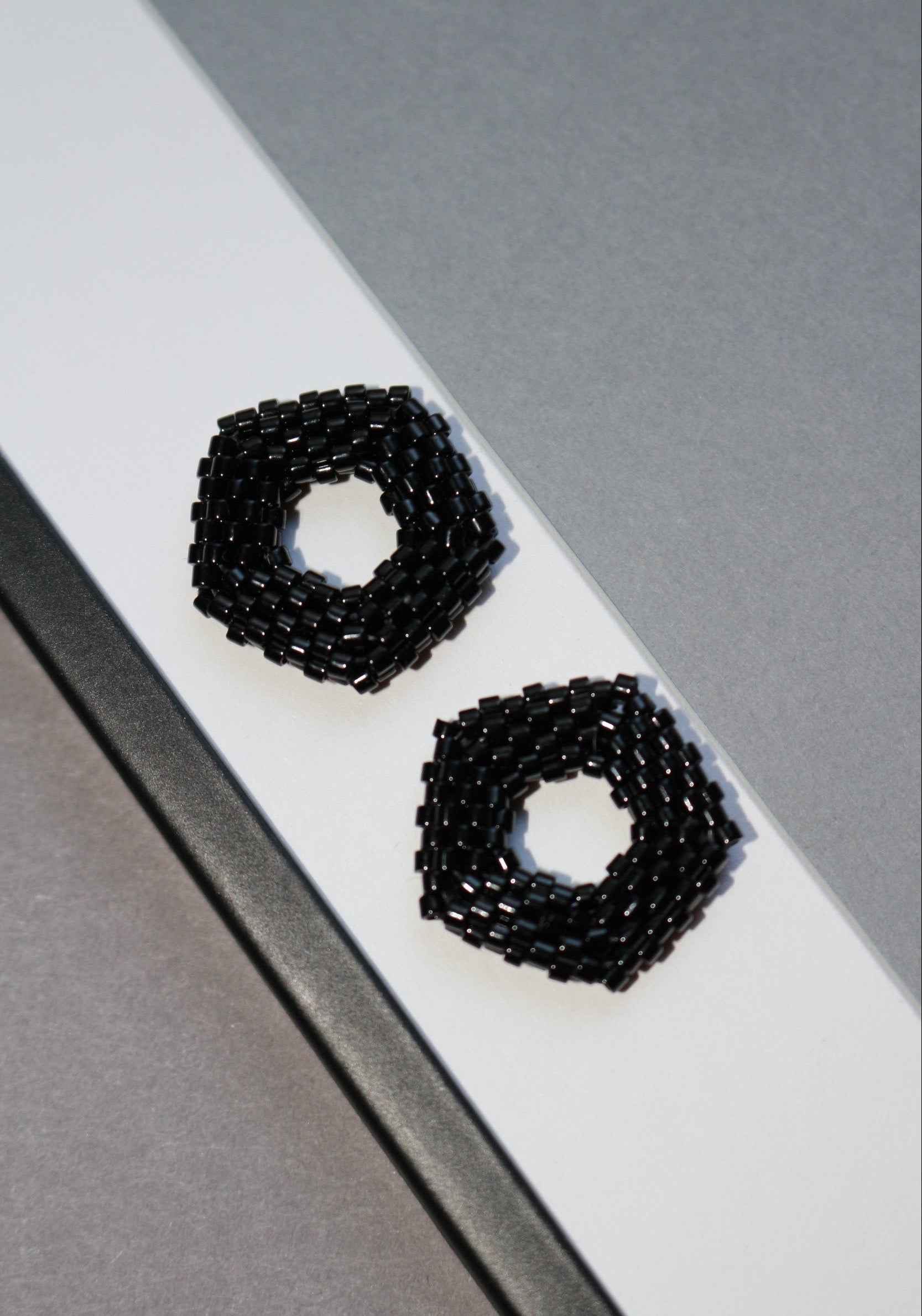 Black beaded pentagon elements on a grey and white background