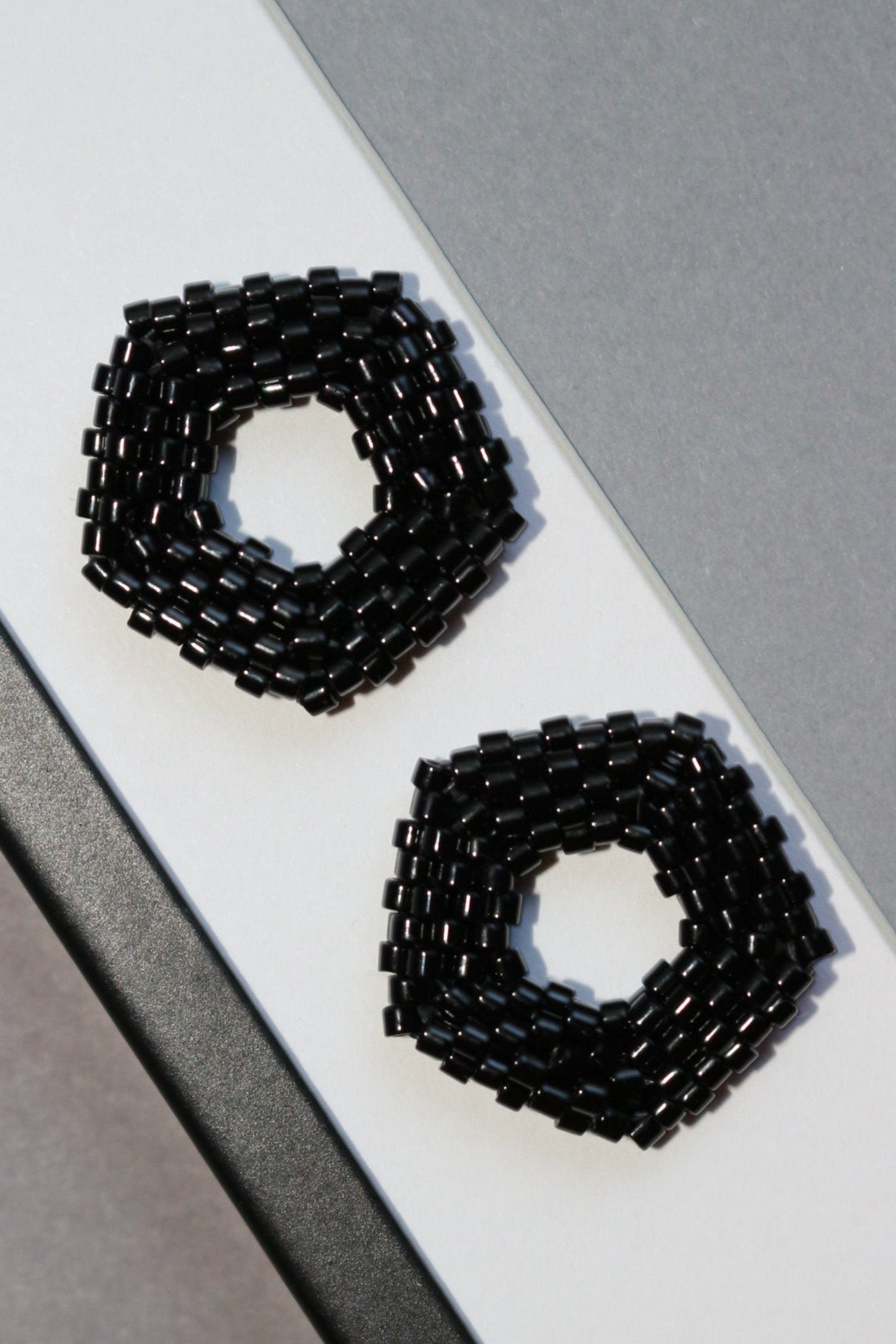 Black beaded earrings on a white and gray background