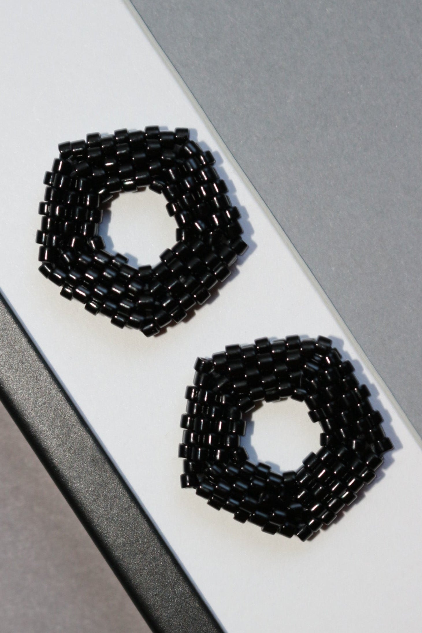 Black beaded earrings on a white and gray background