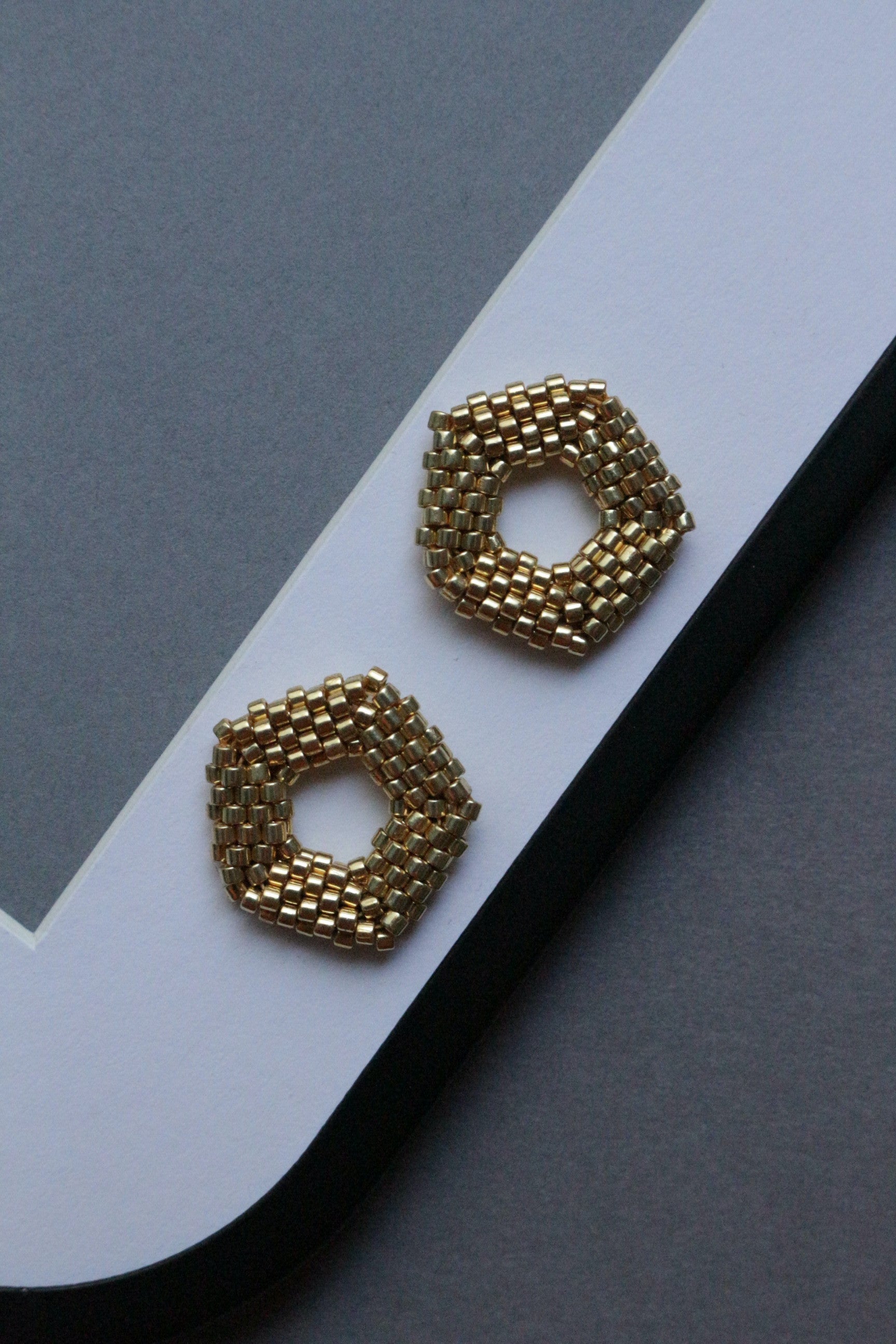 Gold geometric pentagon elements on a white and gray background